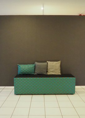 Kuvitekuva vihreästä sohvasta, jonka päällä on kolme tyynyä.